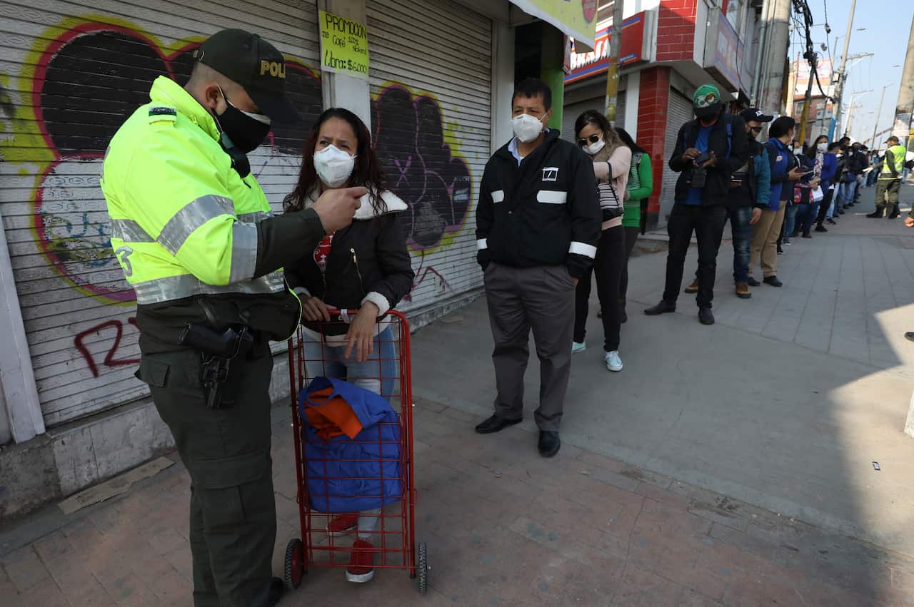 A police officer checks a woman's identification at a public bus station in Soacha on the outskirts of Bogota, Colombia.