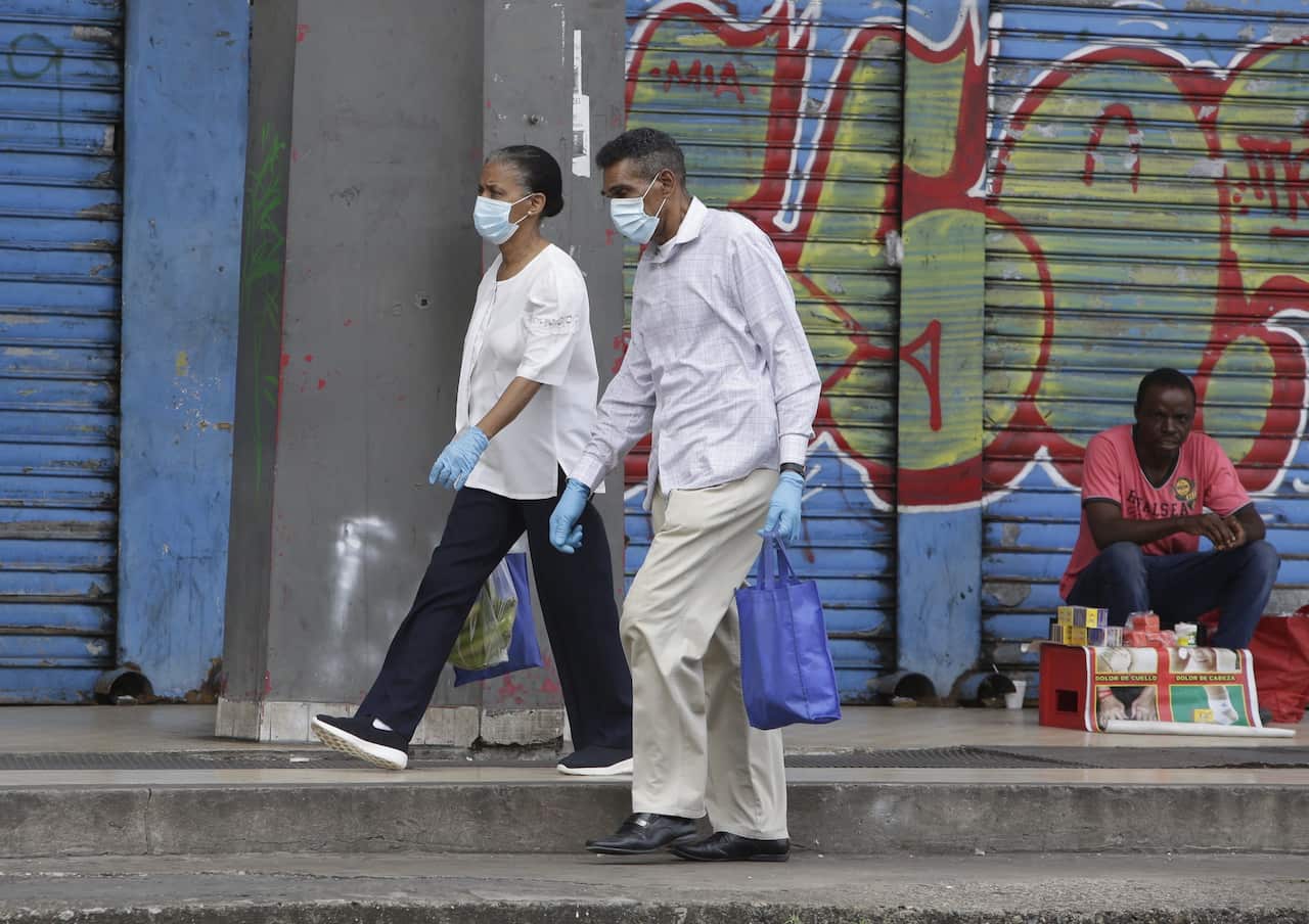 Two people walk wearing masks and gloves in Panama City, Panama, 31 March 2020. Panama accumulates 27 deaths and 1,075 confirmed cases of COVID-19 disease caused by the SARS-CoV-2 coronavirus pandemic. EPA/Carlos Lemos