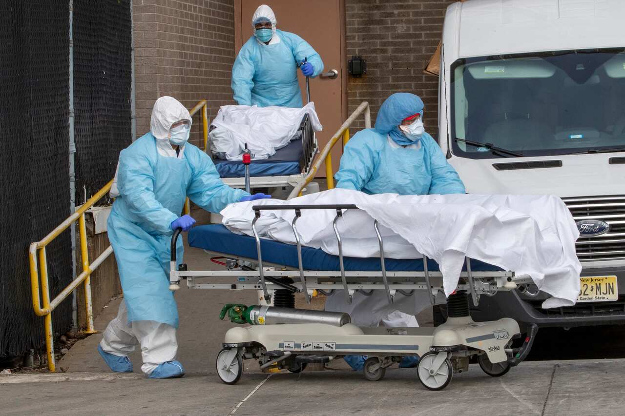 Medical personnel wearing personal protective equipment remove bodies in New York.