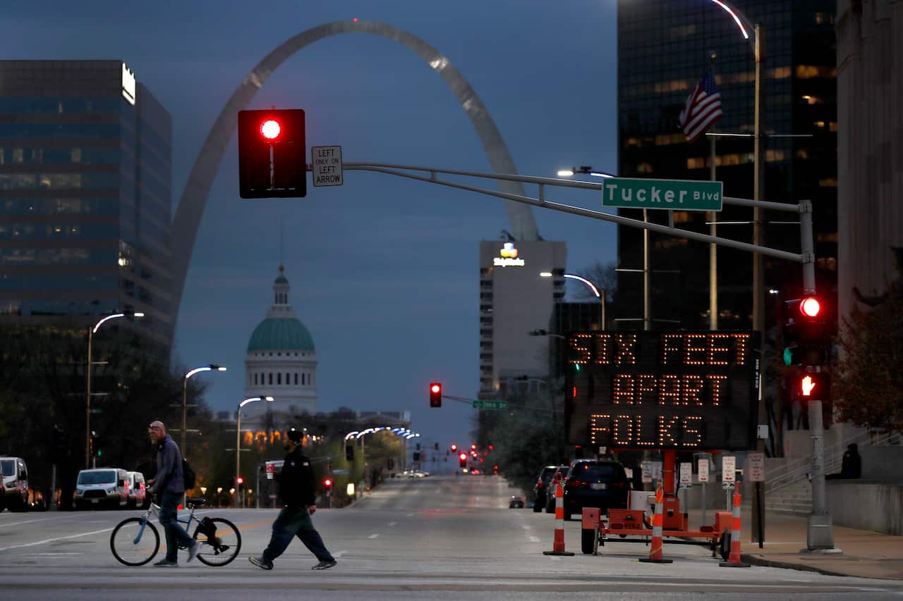 People cross a street near a sign encouraging social distancing in St Louis, US.