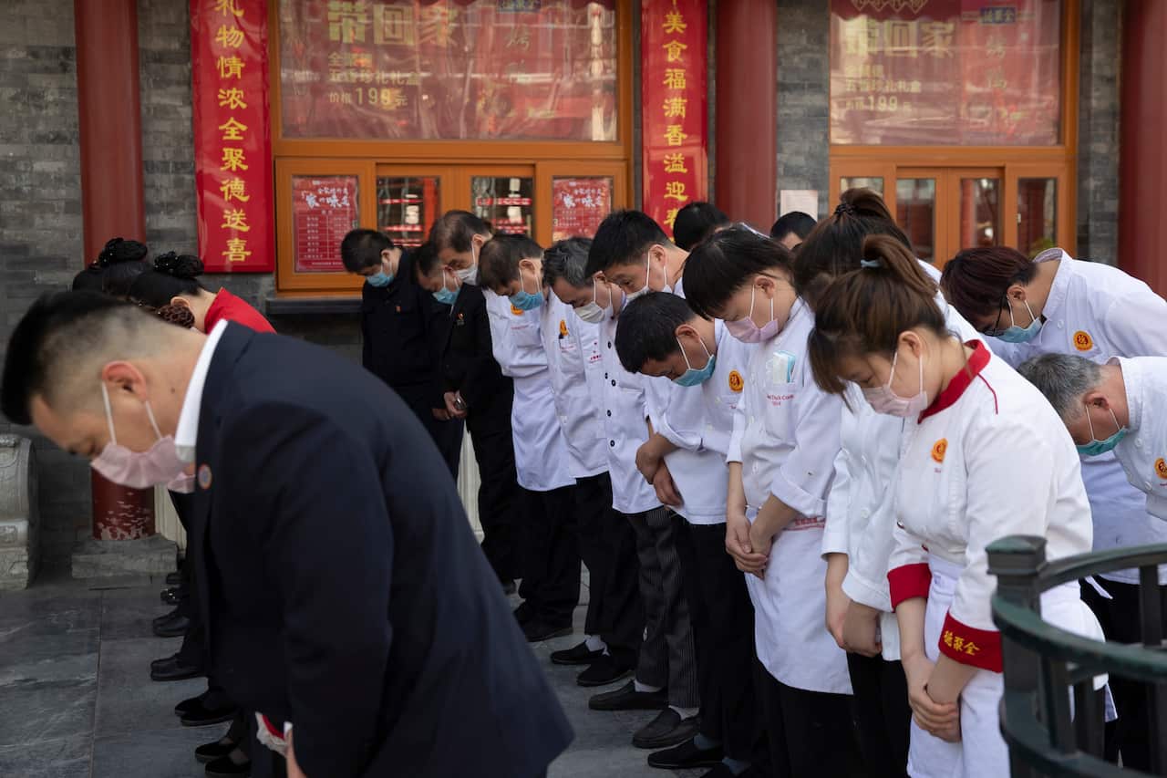 Employees of a restaurant in Beijing gather to mourn those killed by the health pandemic.