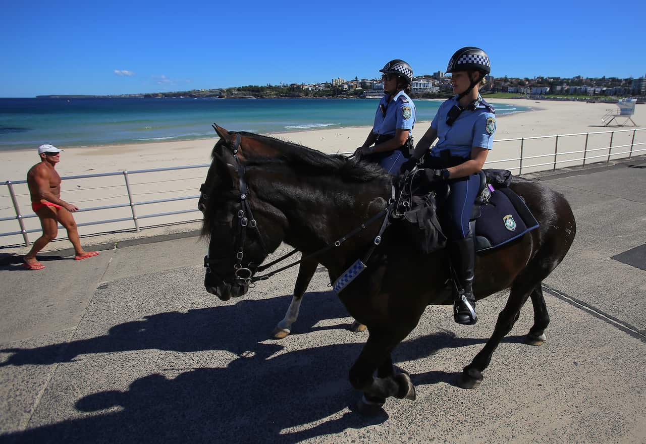 Police on horses enforce social distancing regulations at Bondi Beach.