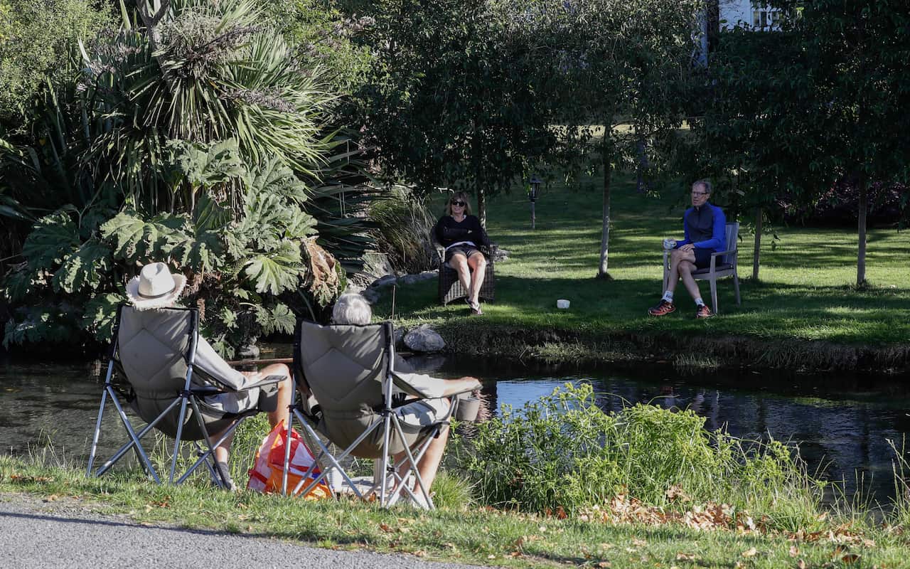 Neighbours chat across a stream as they practice social distancing in a suburb of Christchurch, New Zealand.