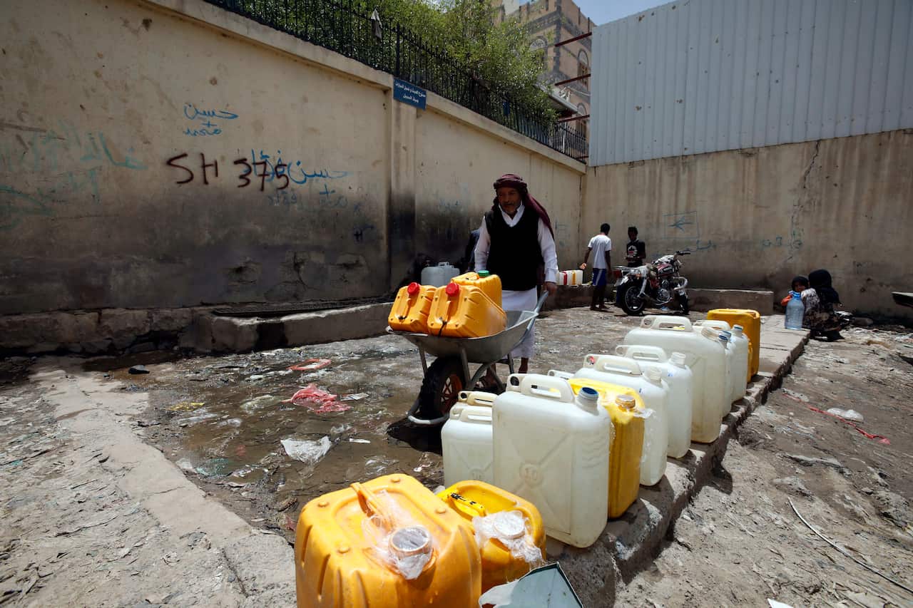 A Yemeni man pushes a wheelbarrow with water-full jerrycans after filling them from a charity tap amid concerns over the spread of the coronavirus.