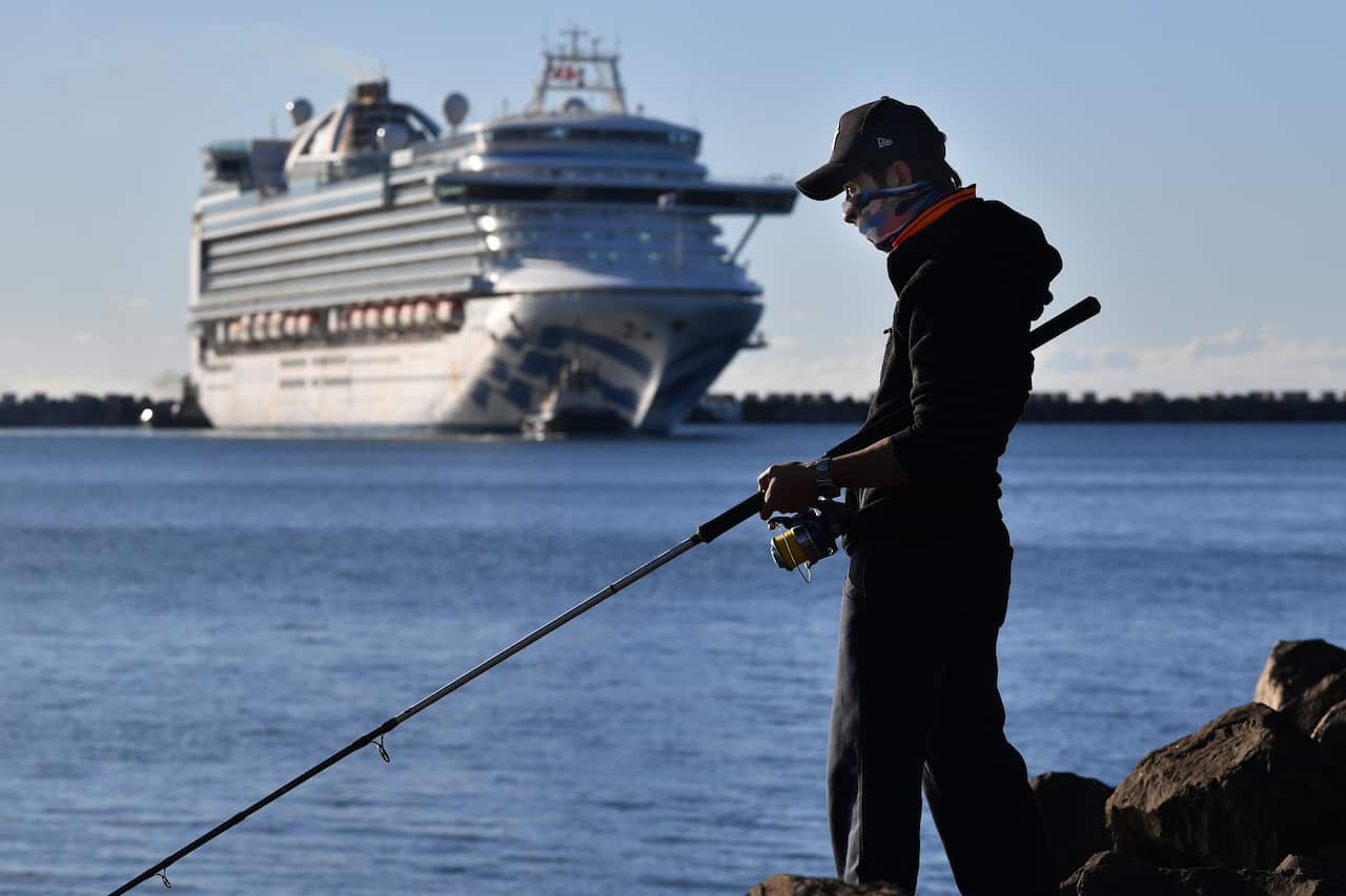 A fisherman wearing a face mask looks on as the Ruby Princess docks at Port Kembla, Wollongong, NSW.
