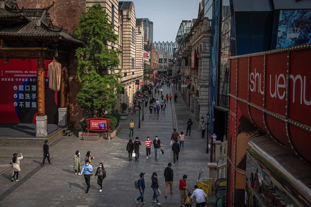 People wearing protective face masks walk at a shopping area in Wuhan, China.