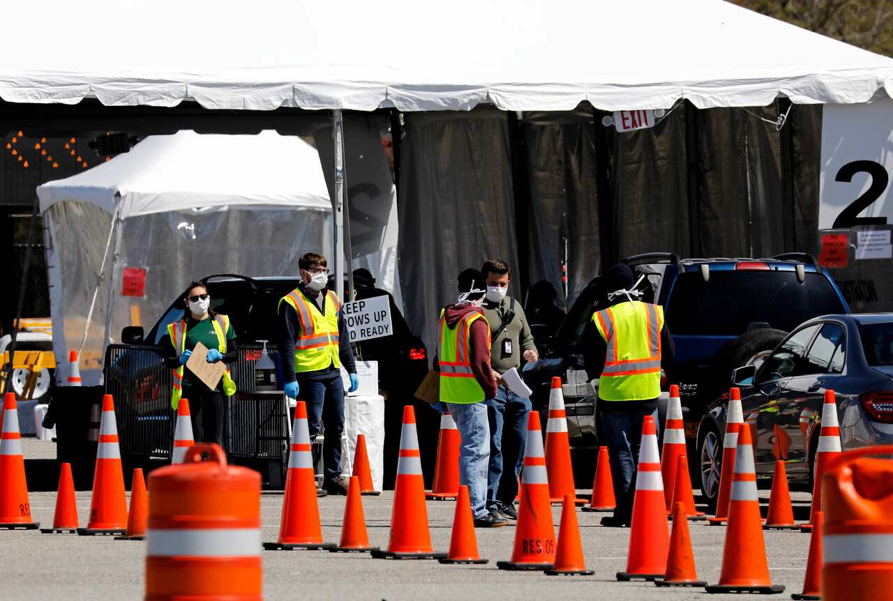Workers direct people queueing up in theirs cars waiting to be tested for coronavirus COVID-19 at the drive-in test site in New York.