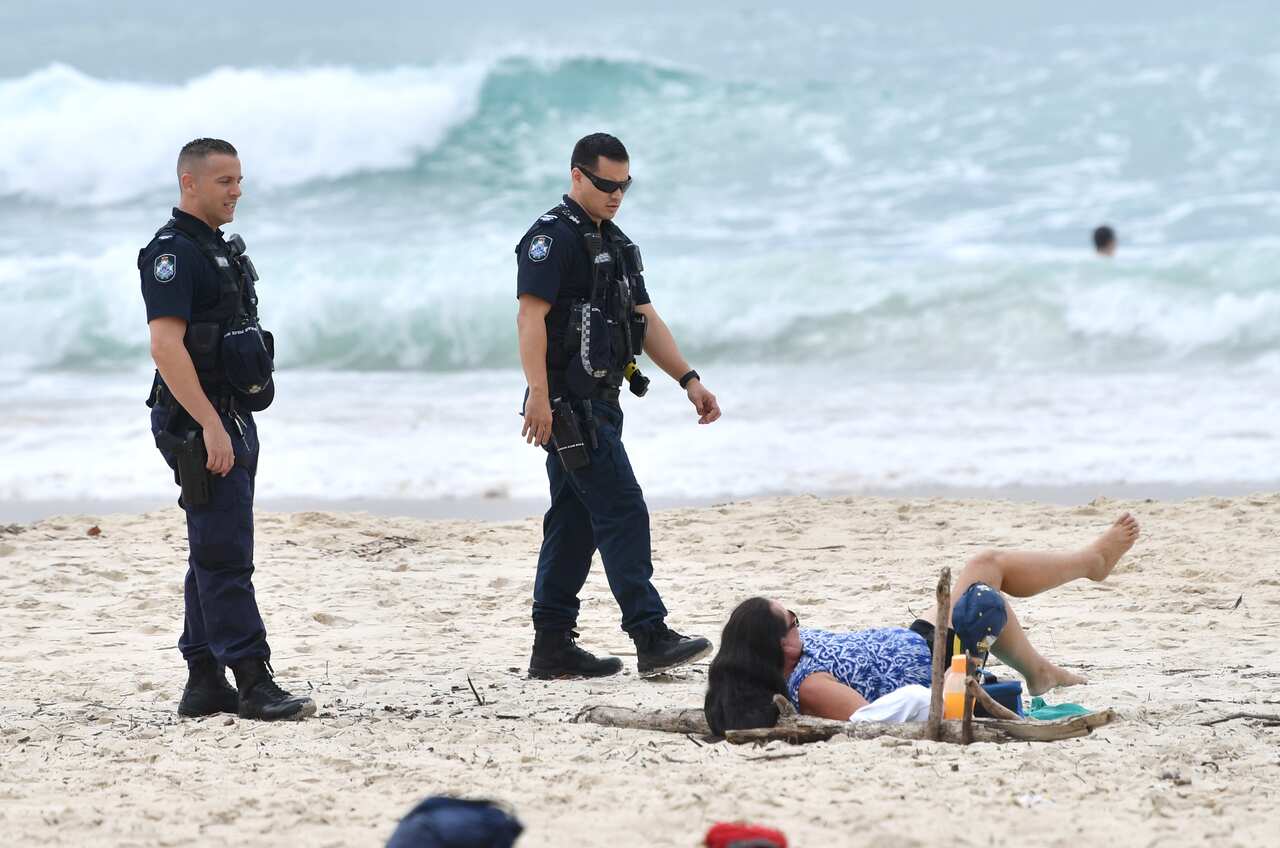 Queensland Police are seen moving on a sunbather from the beach at Burleigh Heads on the Gold Coast.