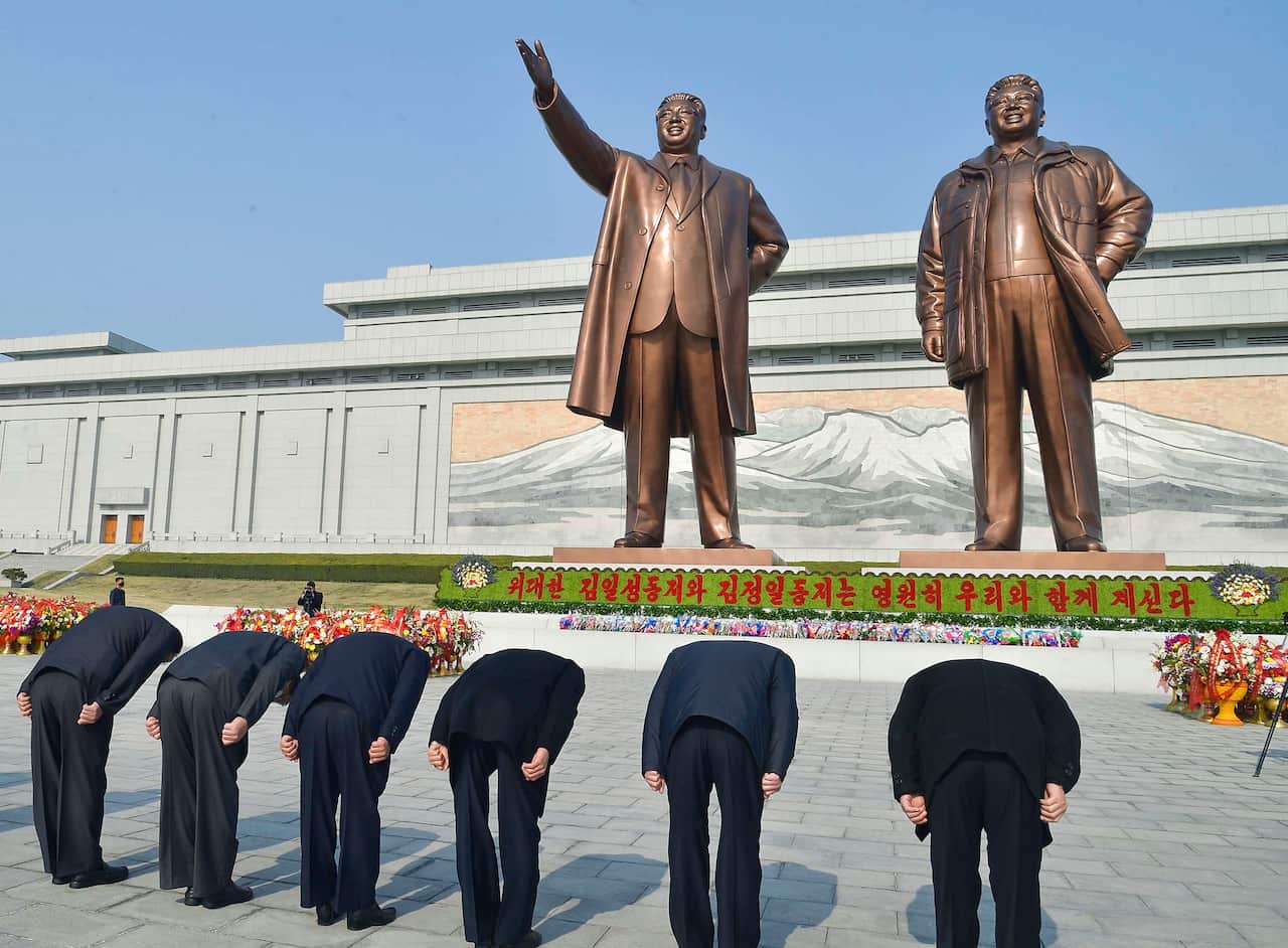 People bow to statues of North Korea's founder Kim Il Sung (L) and his son Kim Jong Il on Mansu Hill in Pyongyang on April 15, 2020, the 108th anniversary of the founder's birth.