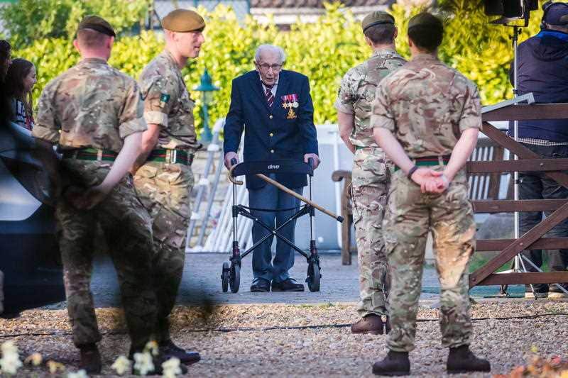 99-year-old British veteran Captain Tom Moore (C) completes the 100th length of his back garden