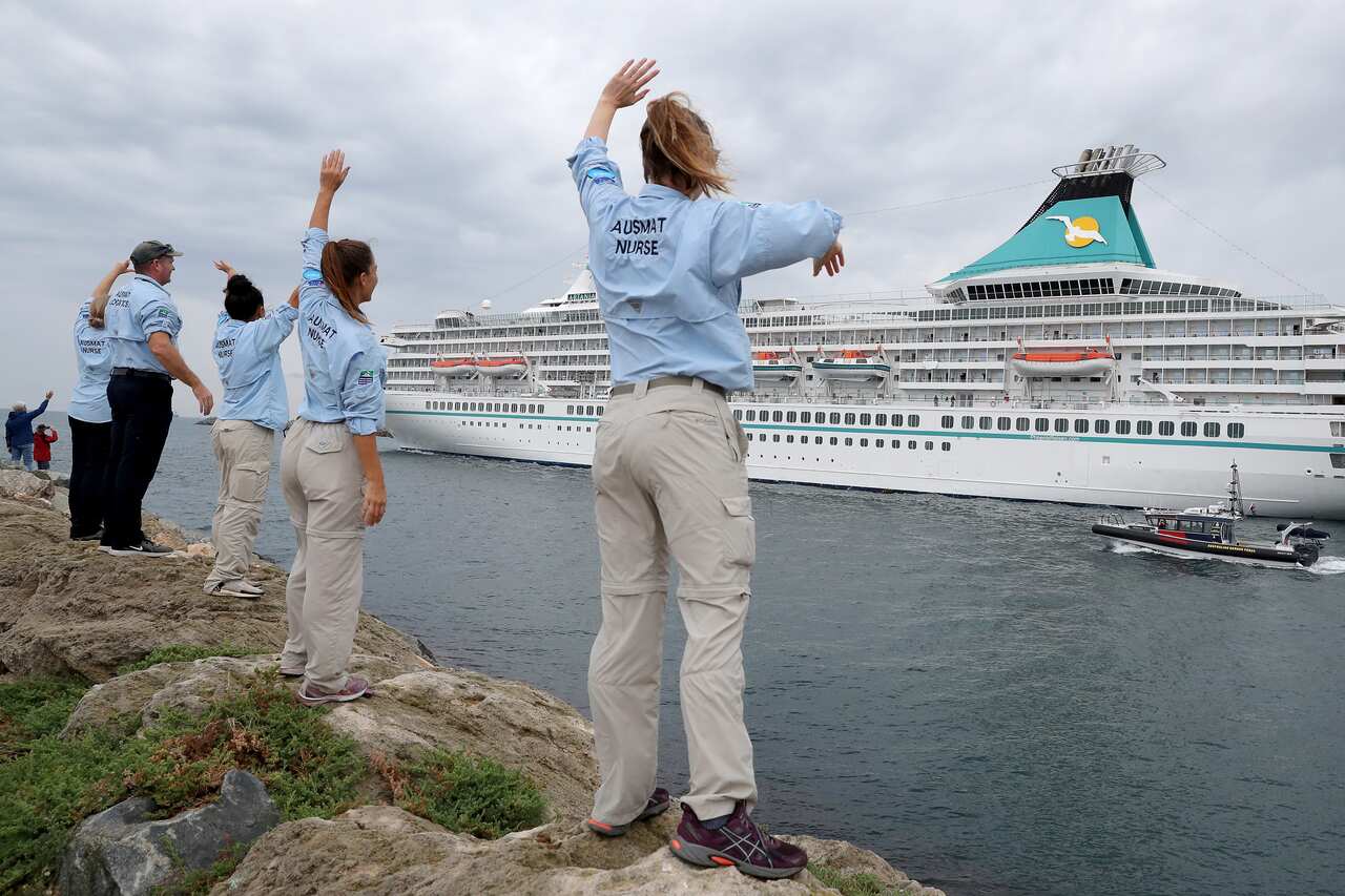 Australian Medical Assistance Team staff who worked with the passengers and crew on the cruise ship Artania wave goodbye as it departs Fremantle harbour.