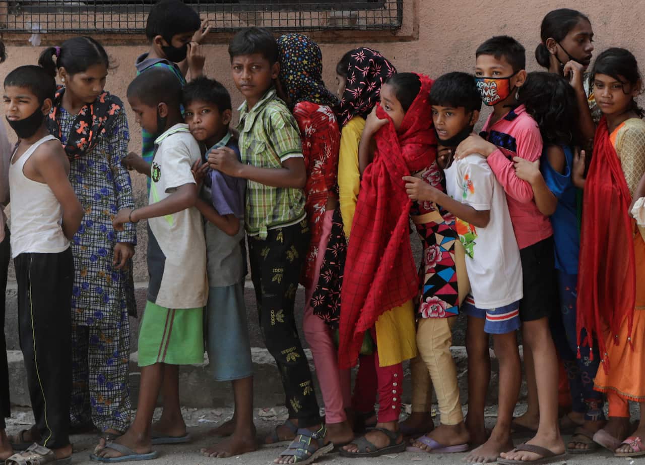 Children wait in a queue to receive food distributed in a slum during India's coronavirus lockdown.