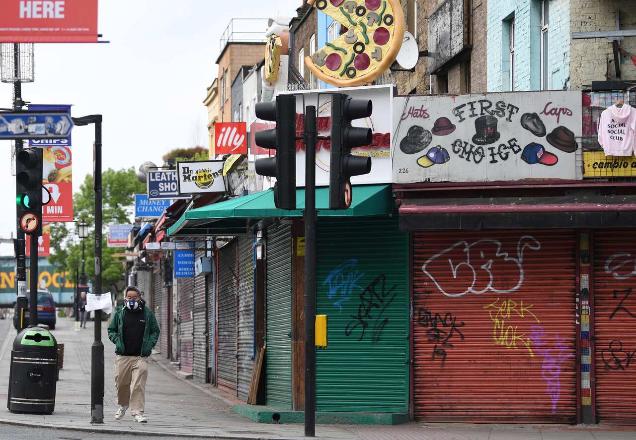 A masked man passes closed stores in Camden Town in London, Britain