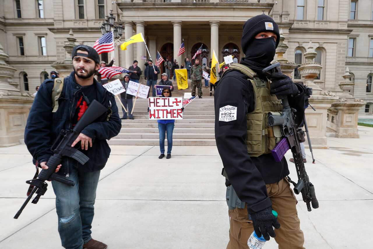 Protesters carry rifles near the steps of the Michigan State Capitol building in Lansing, Michigan.