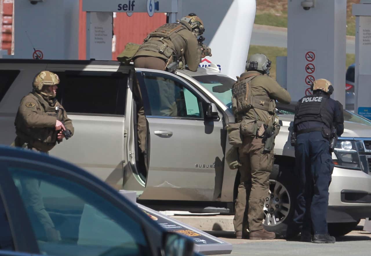 Police officers prepare to take a suspect into custody at a gas station in Enfield, Nova Scotia.