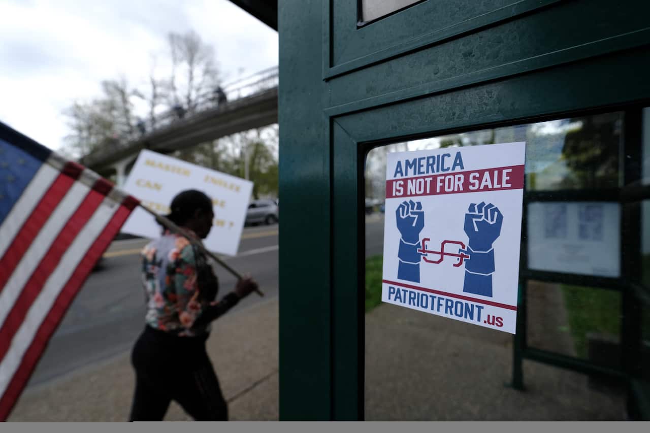A woman walks past a new sticker for the white supremacist Patriot Front group during coronavirus protests in Washington.