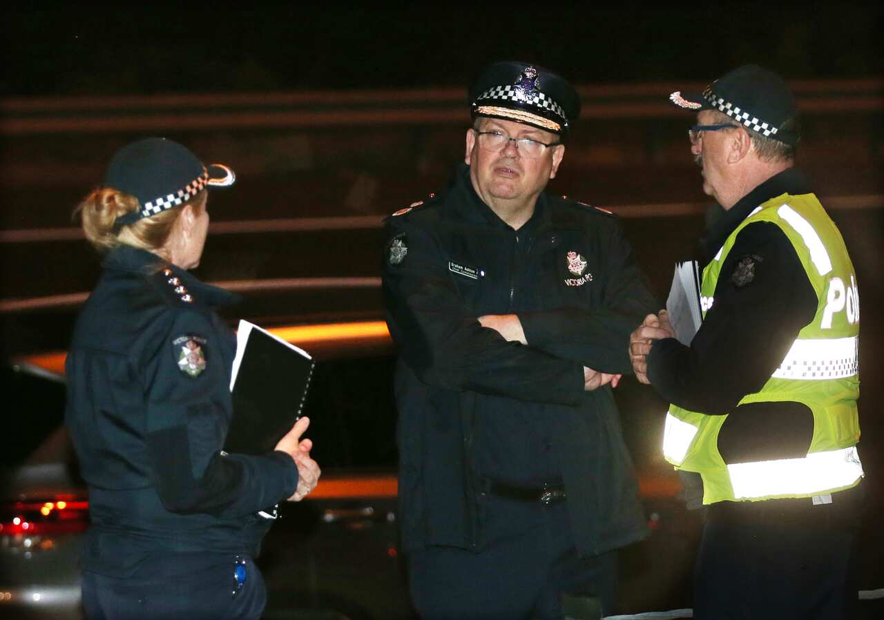 Victoria Police Chief Commissioner Graham Ashton (centre) is seen near where emergency services responded to the collision.