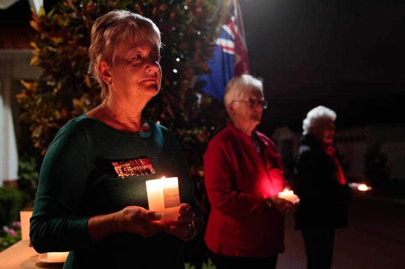 Susan Scott, Suzanne Crockett and Rose-Marie Lockwood, residents at a retirement village hold candles at dawn on Anzac Day.
