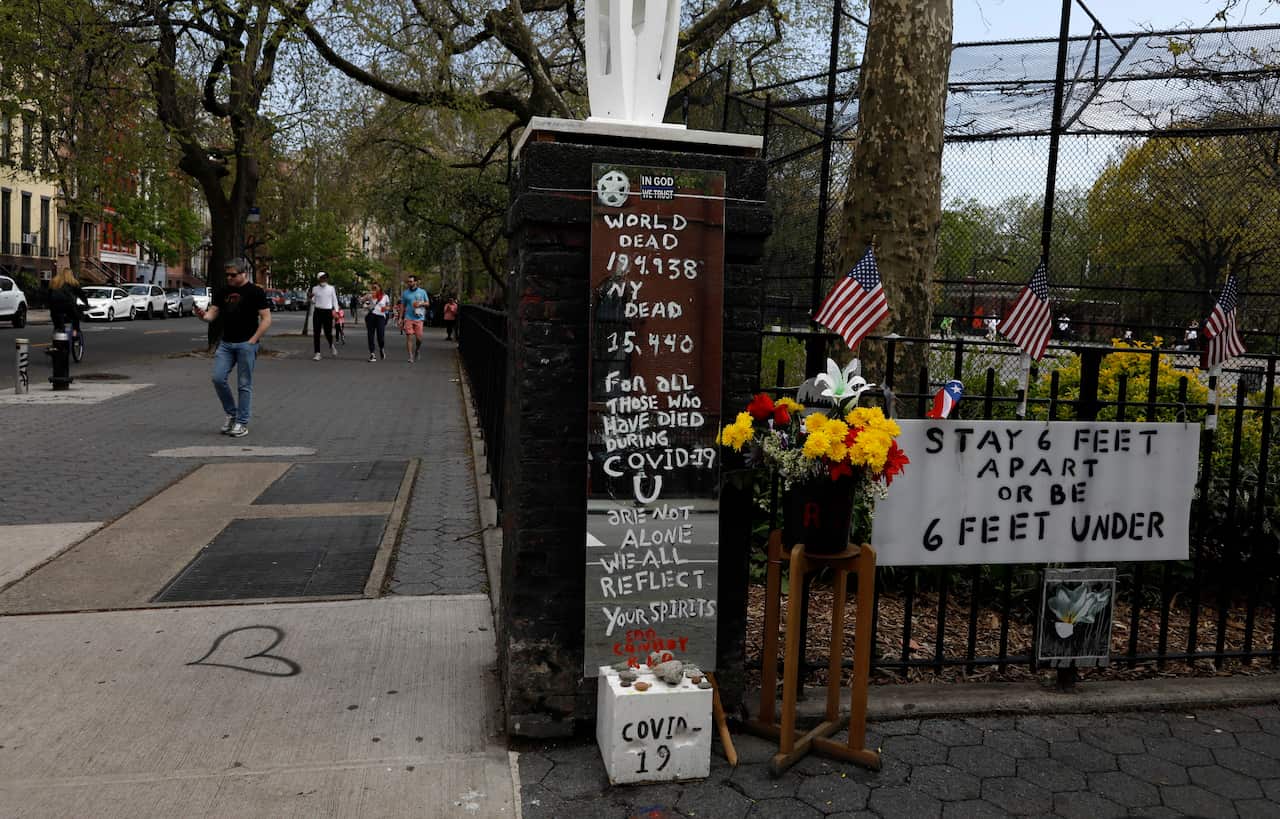 People without masks walk past a memorial outside of Tompkins Square Park in the Alphabet City neighbourhood of New York.