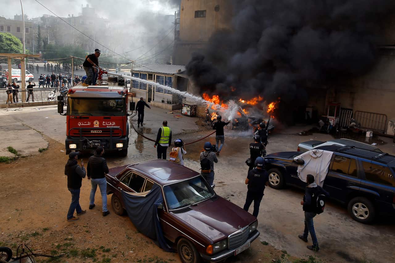 Firefighters extinguish a police car that was set on fire by anti-government protesters, in the northern city of Tripoli in Lebanon. 