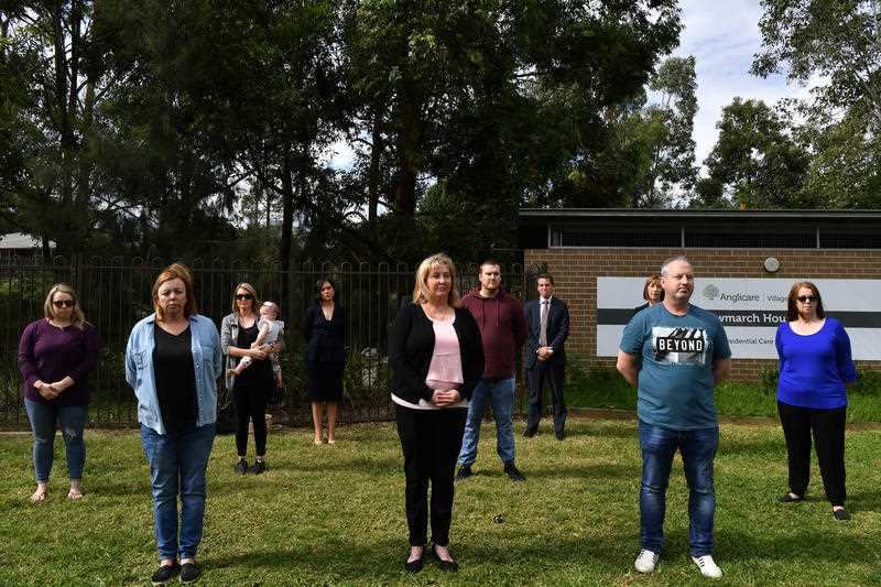 Family members of residents of Anglicare's Newmarch House practice social distancing as they stand outside the aged care home in Kingswood, near Penrith.