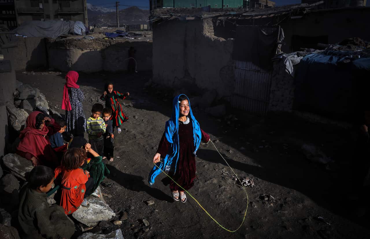  An internally displaced Afghan girl plays with skipping rope outside of her temporary shelter in Kabul, Afghanistan. 
