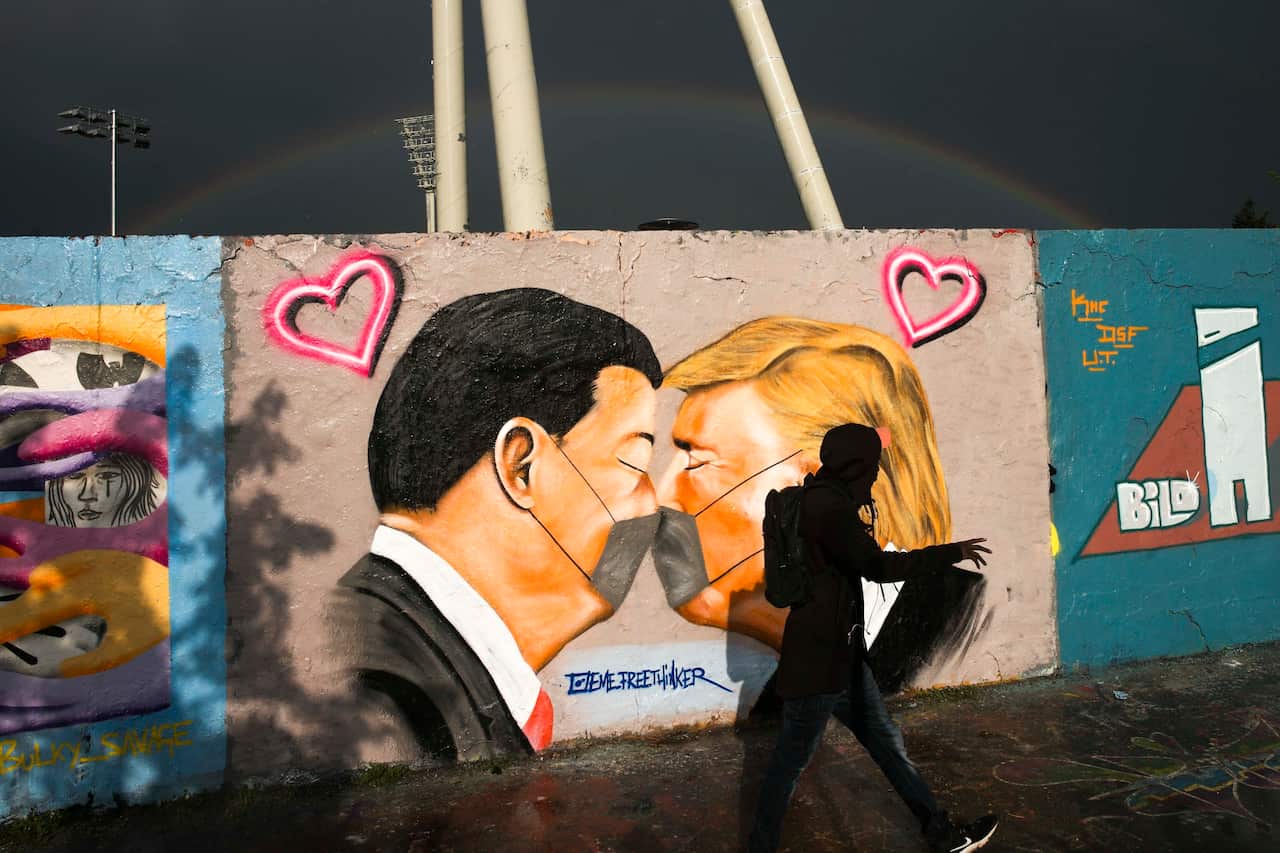 Graffiti depicting US President Trump, right, and China's President Xi Jinping kissing each other with face masks, displayed at a wall in Berlin, Germany.