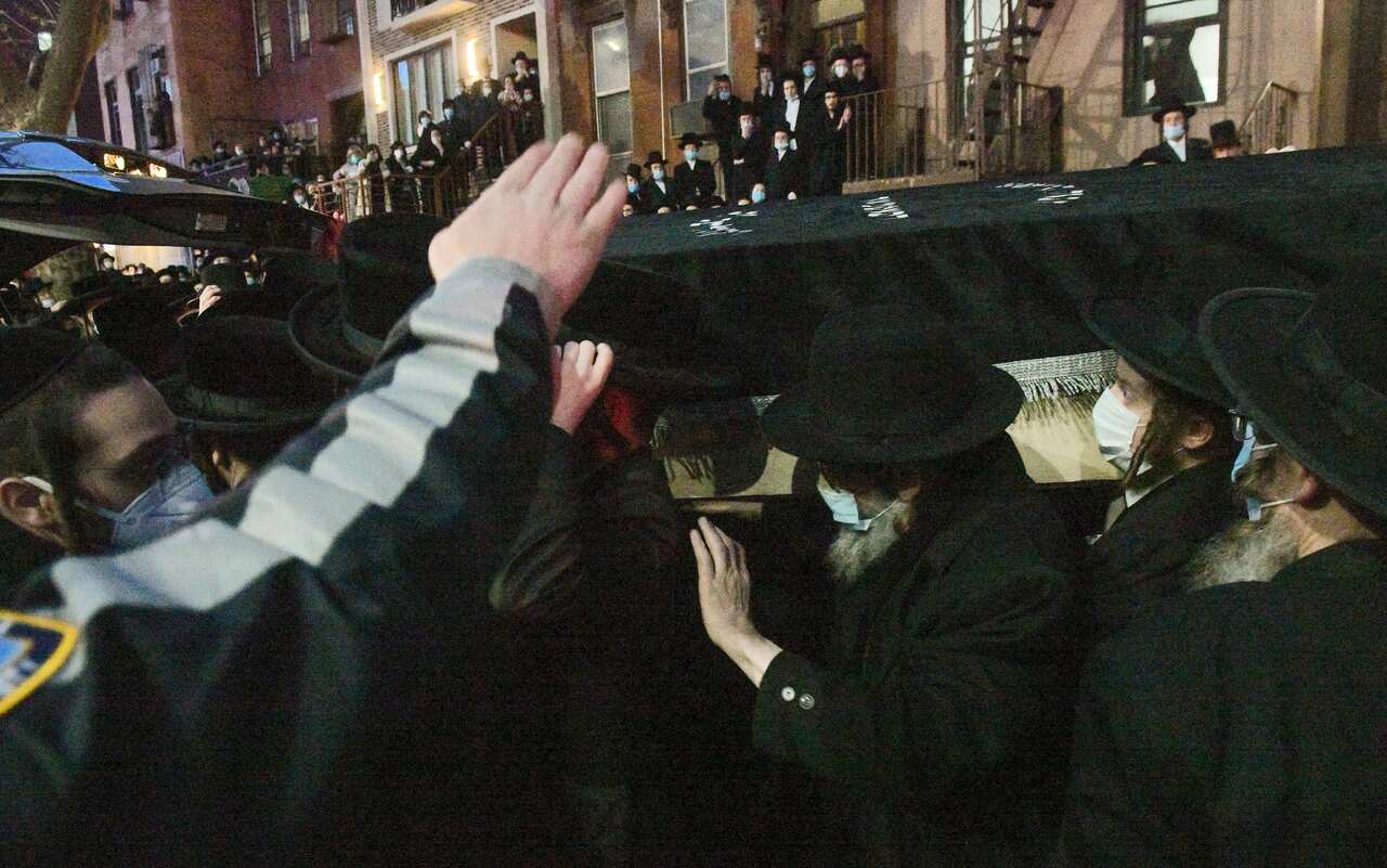 Mourners make their way through a crowd in New York City while carrying the casket of Rabbi Chaim Mertz, a Hasidic Orthodox leader.