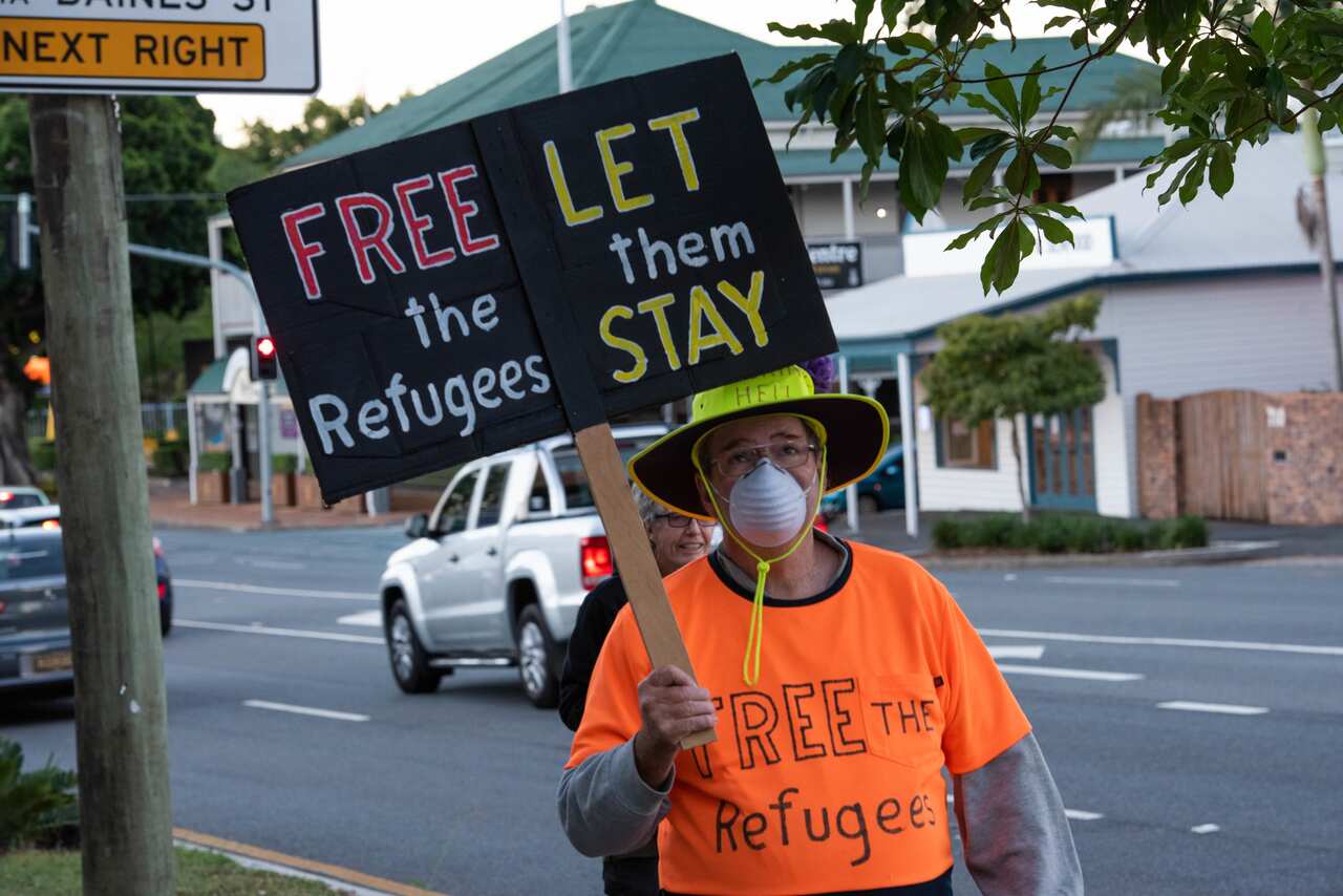 A protester holds a placard saying 'free the refugees, let them stay' during a Brisbane demonstration on Friday. 
