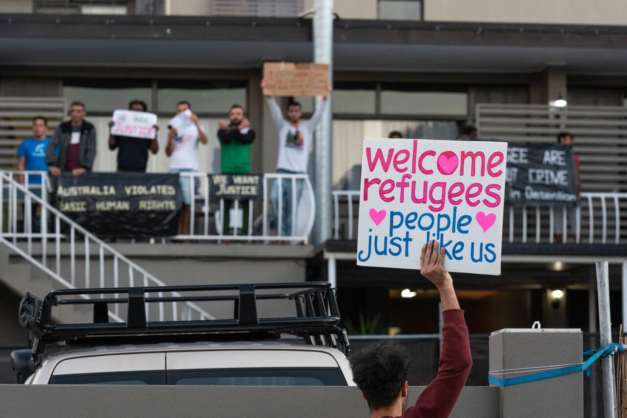 A protester holds a placard saying 'Welcome Refugees - People just like us' during a demonstration in Brisbane.