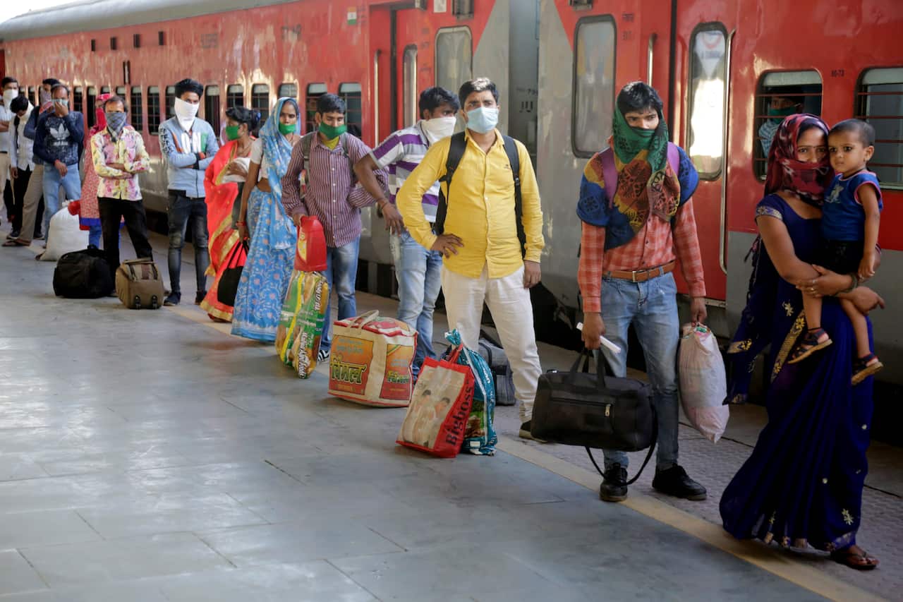 Indian migrated workers stands in queue to board a special train at a railway station in Ahmedabad, India.