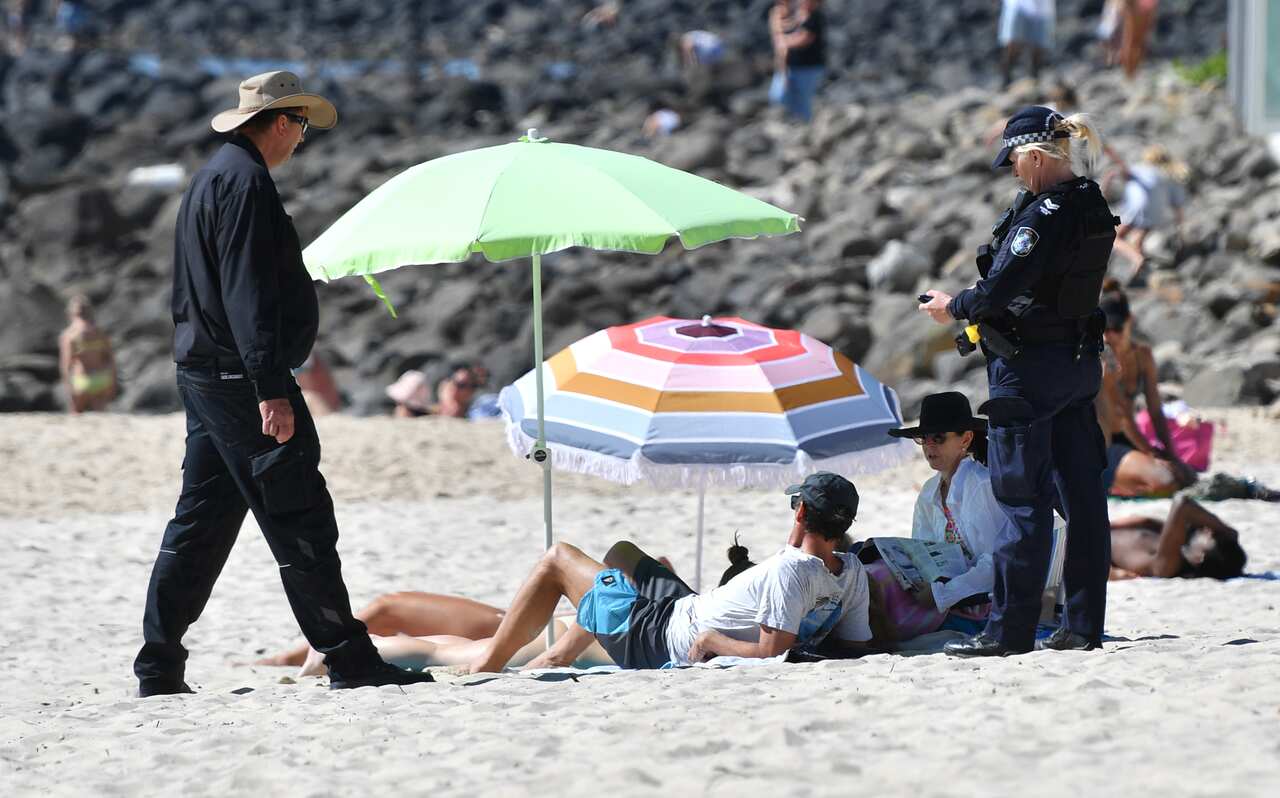 A police officer speaks to beachgoers at Burleigh Heads on Queensland's Gold Coast.