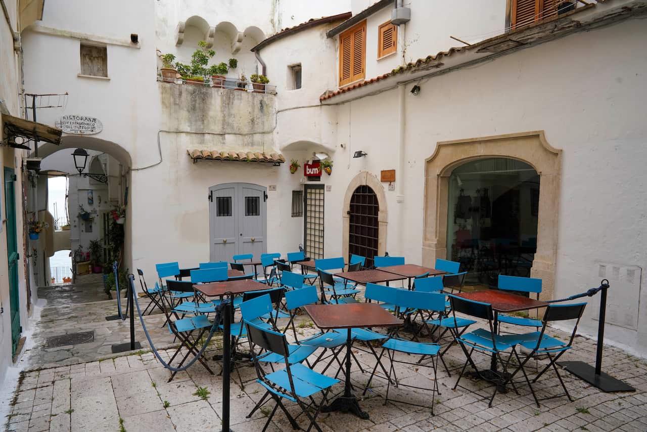 Tables and chairs are seen in front of a closed restaurant, in the seaside town of Sperlonga, Italy.