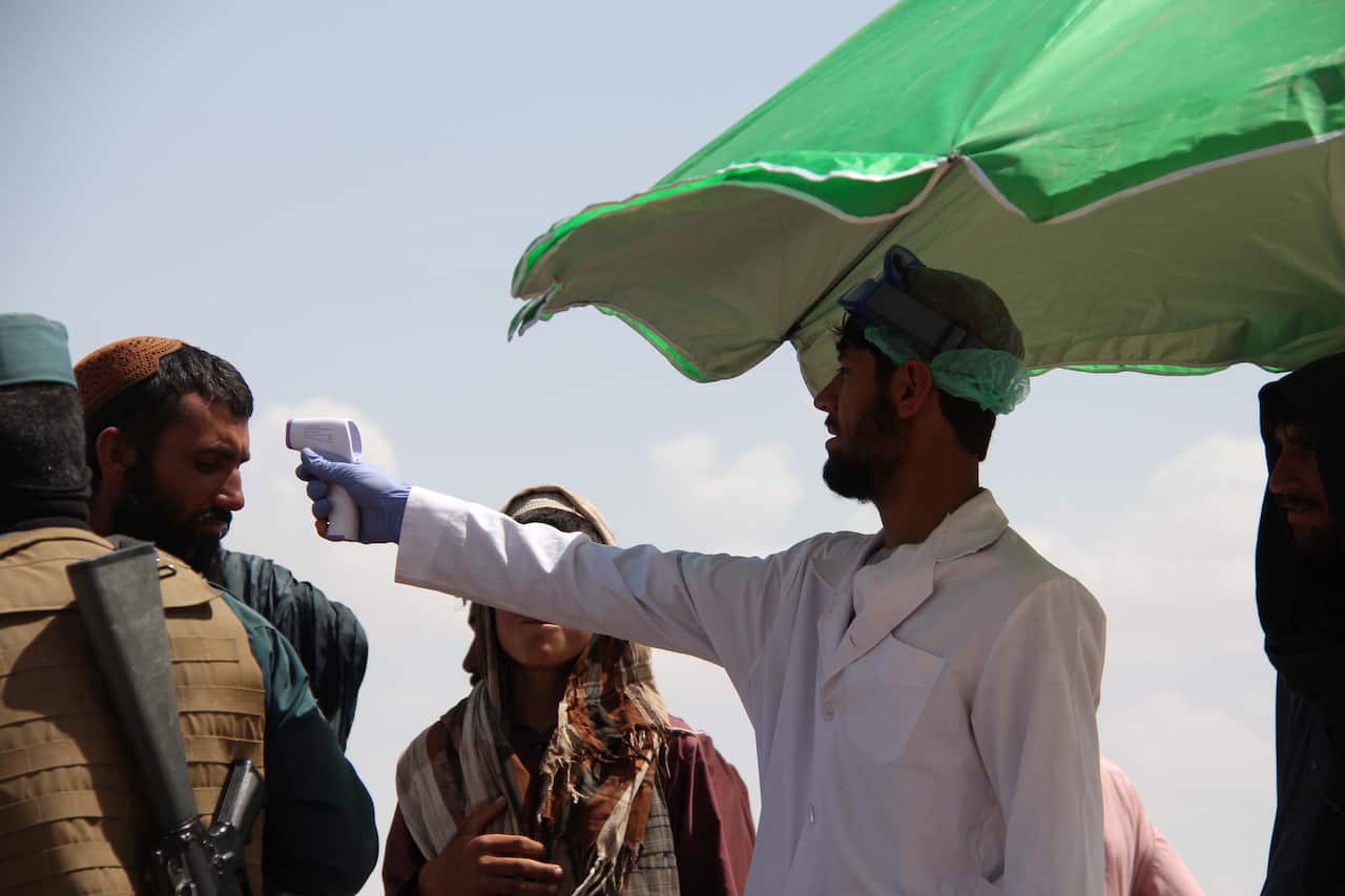 An Afghan health worker checks the body temperature of people to prevent the spread of the SARS-CoV-2 coronavirus. 
