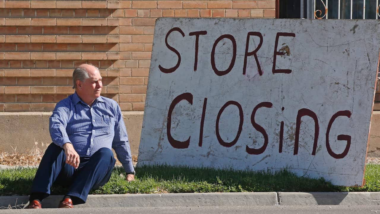 Euro Treasures Antiques owner Scott Evans poses next to his store closing sign in Salt Lake City.