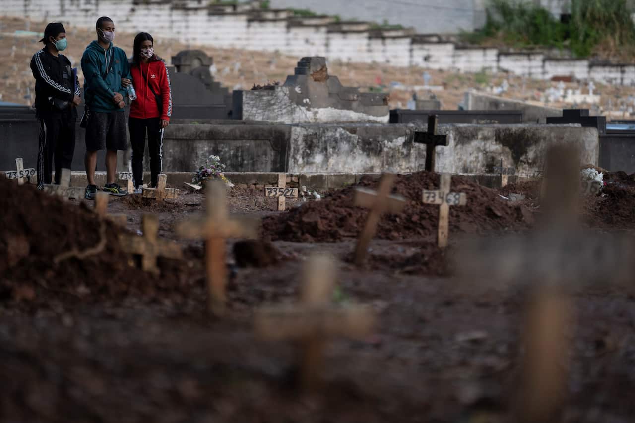 Relatives, wearing protective face masks, attend the burial of 71-year-old Neide Rodrigues Rosa, who died from the new coronavirus according to her son Sergio Rodrigues, in Rio de Janeiro, Brazil, Friday, May 8, 2020. (AP Photo/Leo Correa)