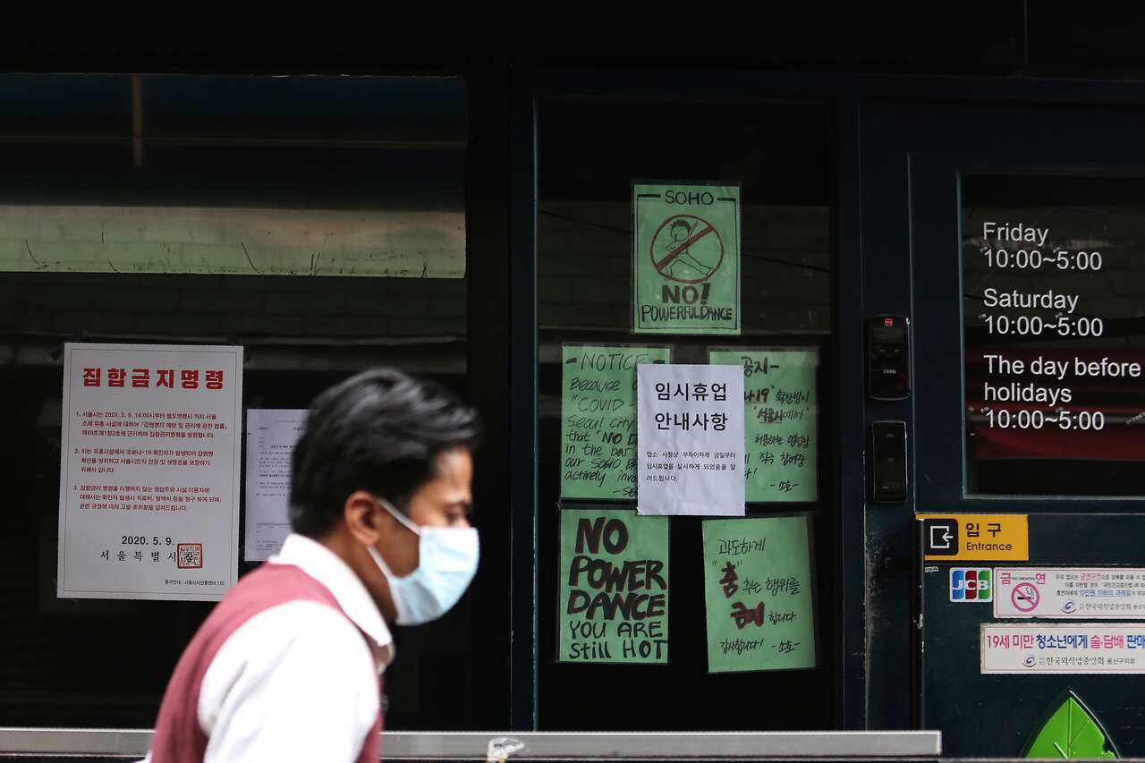 A man waring a face mask passes by notices at the entrance of a temporary closed dance club in Seoul, South Korea, Sunday, May 10, 2020