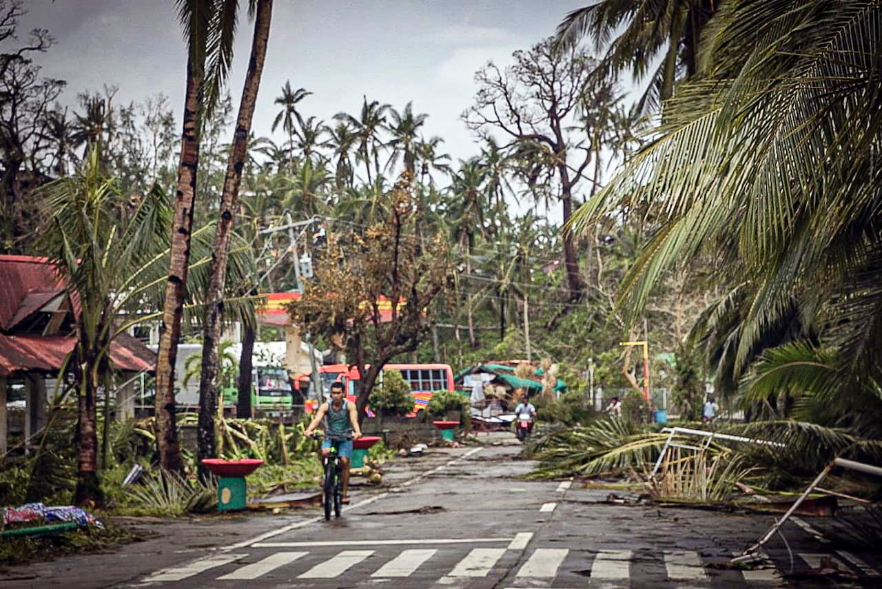 Citizens go past fallen trees and debris on the road due to effects of Typhoon Vongfong in San Policarpio town, Eastern Samar province, Philippines.