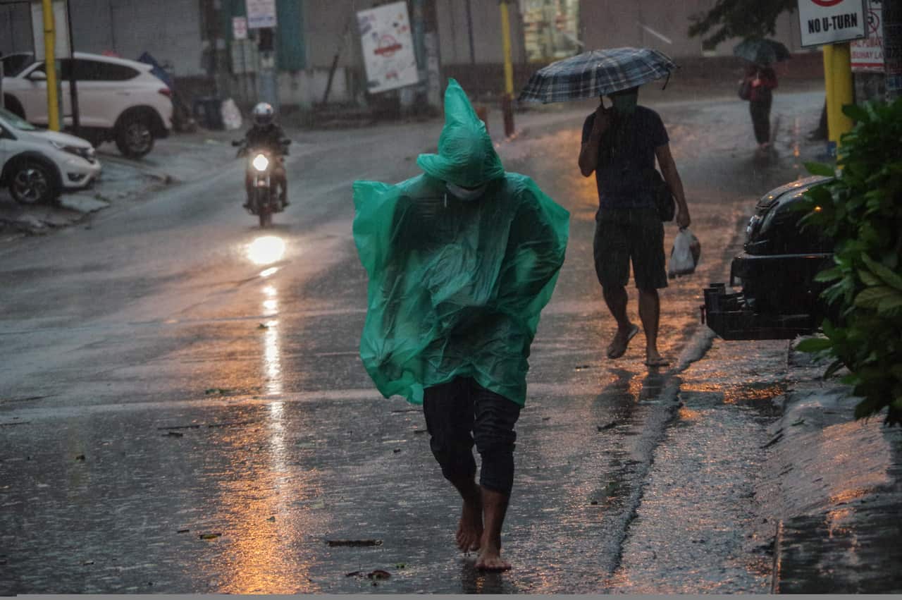 A man wears a plastic poncho as he walks barefoot during strong winds and heavy rains in Mandaluyong City, Philippines.