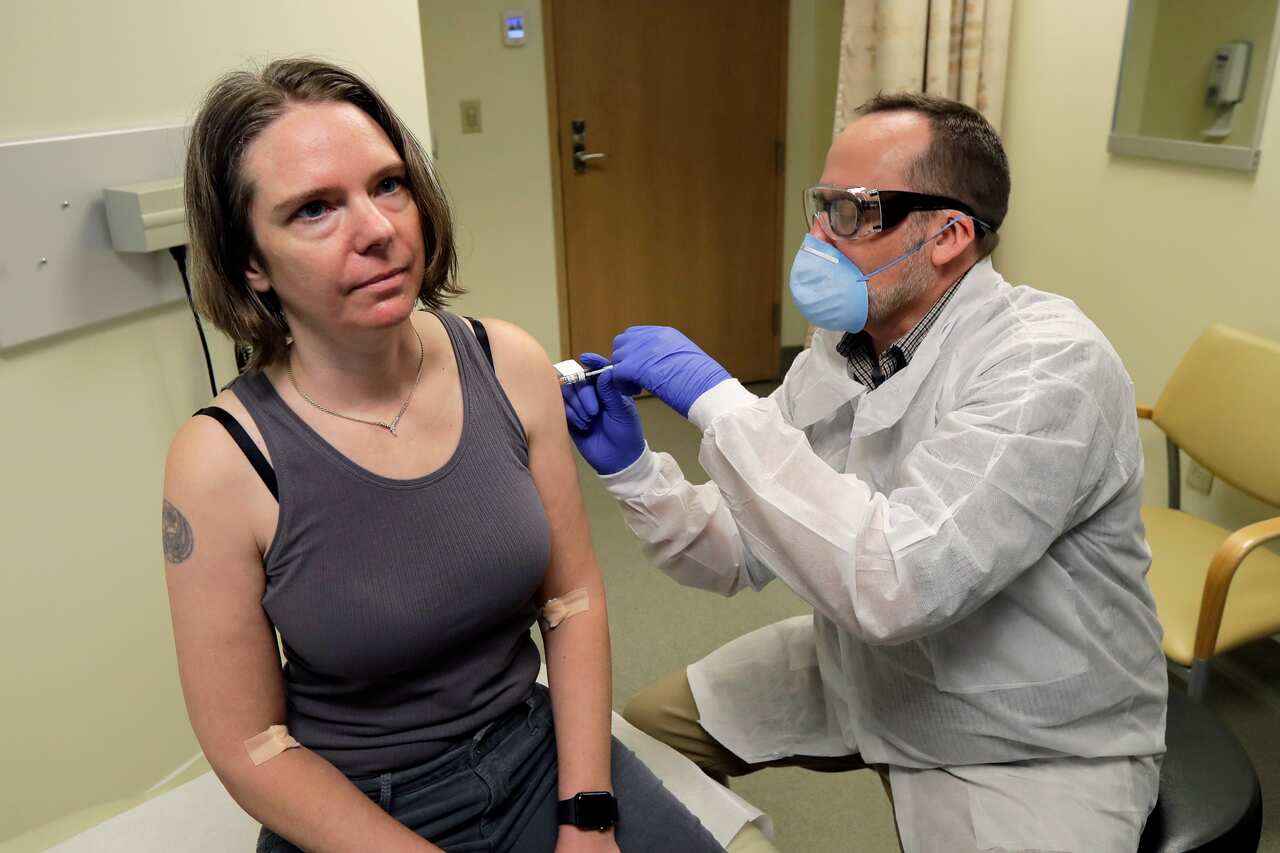 A woman in the US is given the first shot in the clinical trial of a potential vaccine for the COVID-19 coronavirus by a pharmacist.