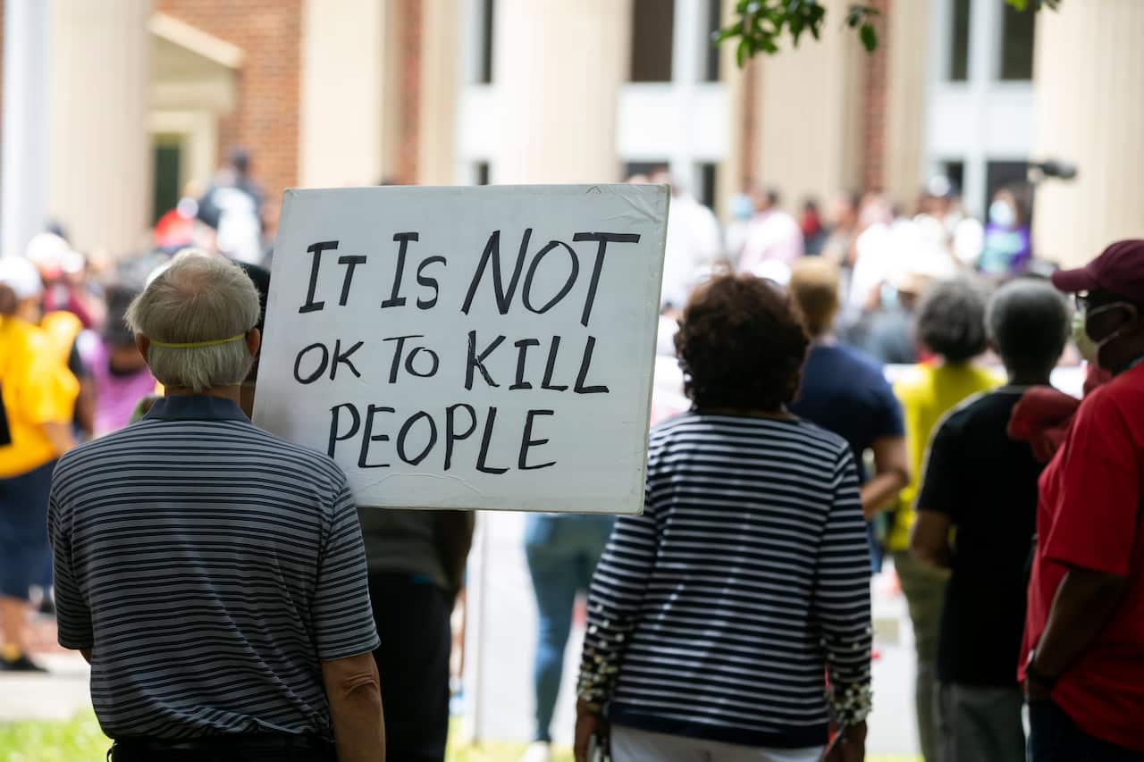 A man holds a sign during a rally to protest the shooting of Ahmaud Arbery, Saturday, May 16, 2020, in Brunswick, Ga. (AP Photo/Stephen B. Morton)