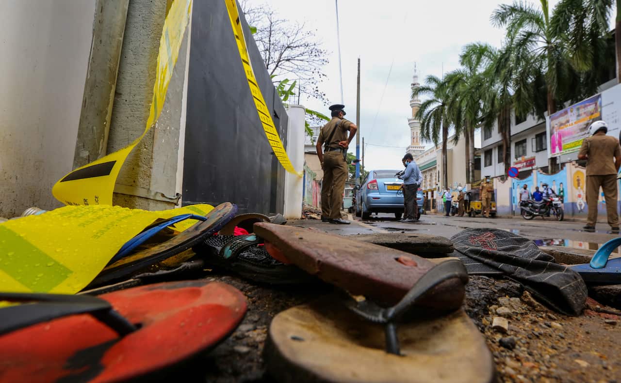 Abandoned footwear litter the rain drenched road while police investigate the stampede caused when a person distributed cash to the needy in Colombo, Sri Lanka.