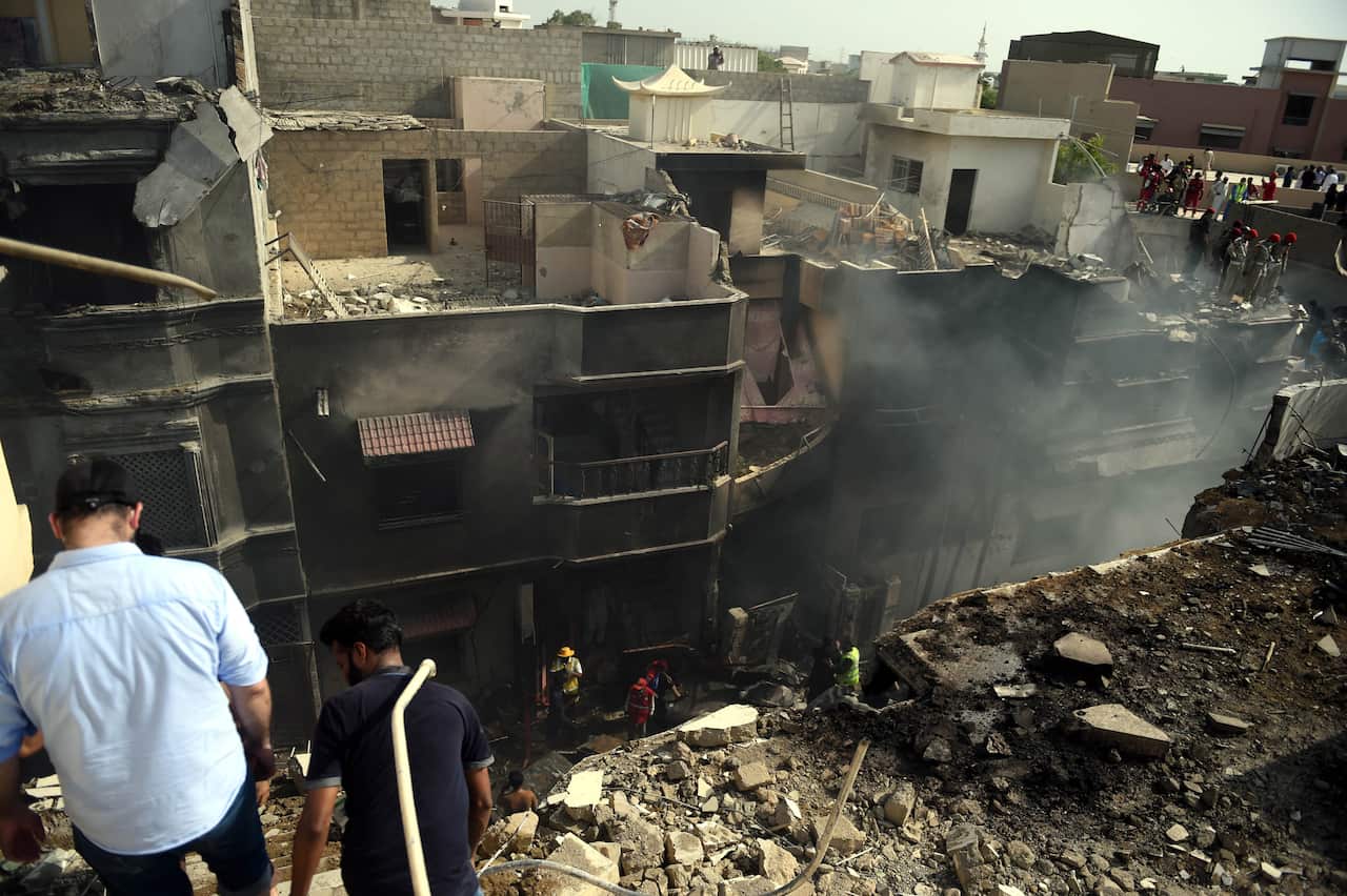 Locals inspect the destruction caused after a passenger plane crashed on a residential colony, in Karachi, Pakistan.