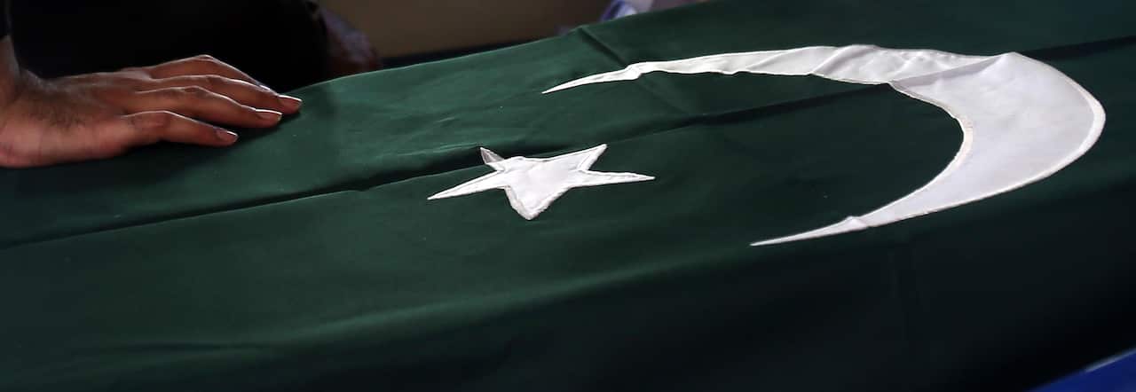 A relative of places his hand on the flag wrapped coffin containing a victim of the Karachi plane crash.