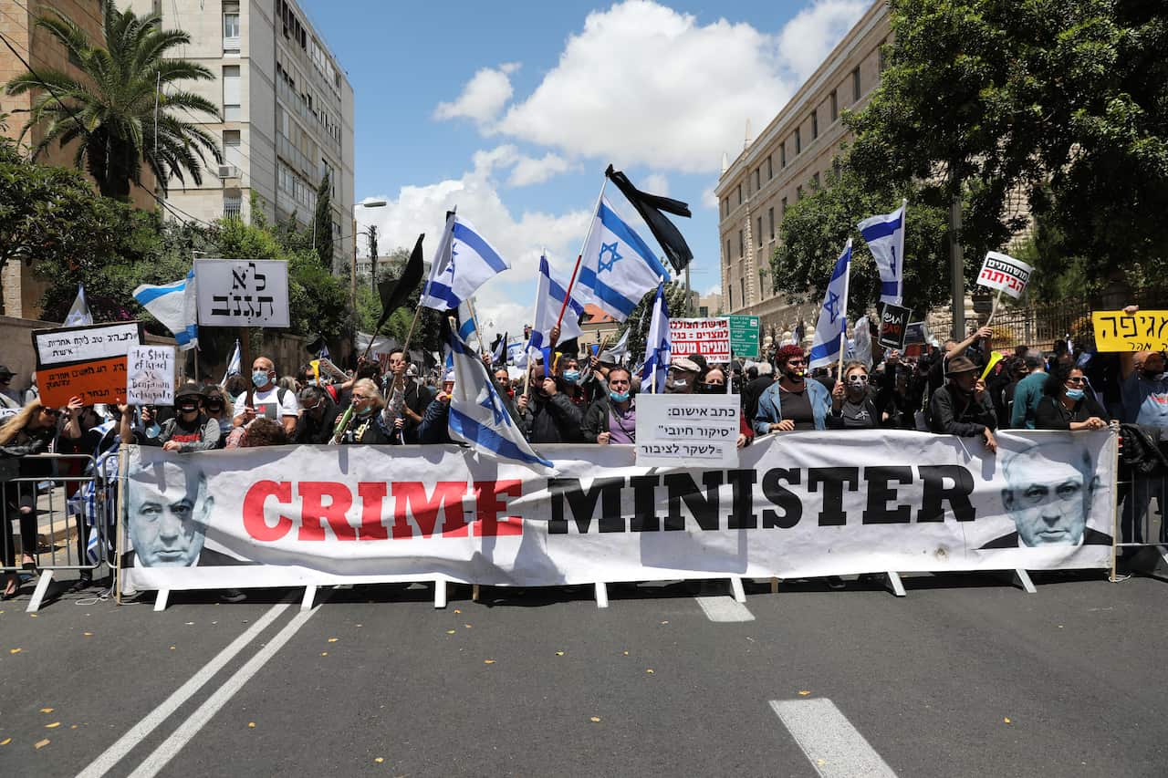 Protesters opposed to Israeli Prime Minister Benjamin Netanyahu march while holding a banner during a protest outside the Prime Minister's Residence