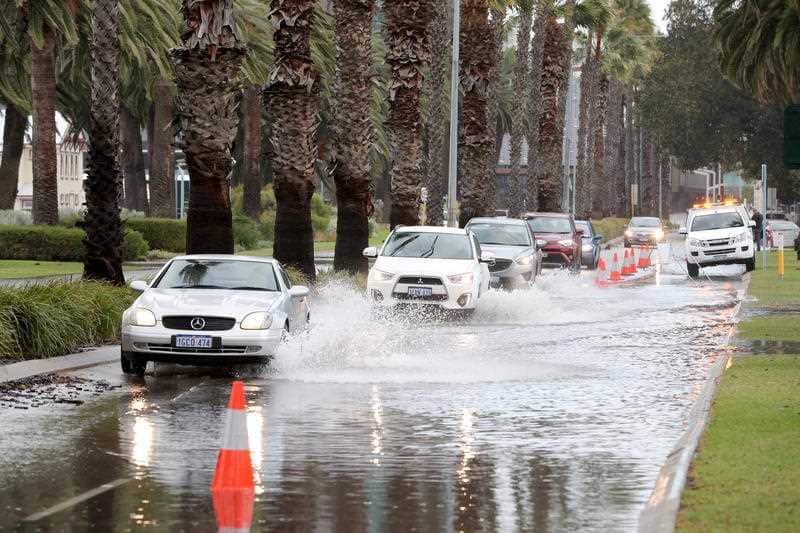 Cars navigate through floodwater on Riverside Drive in Perth CBD