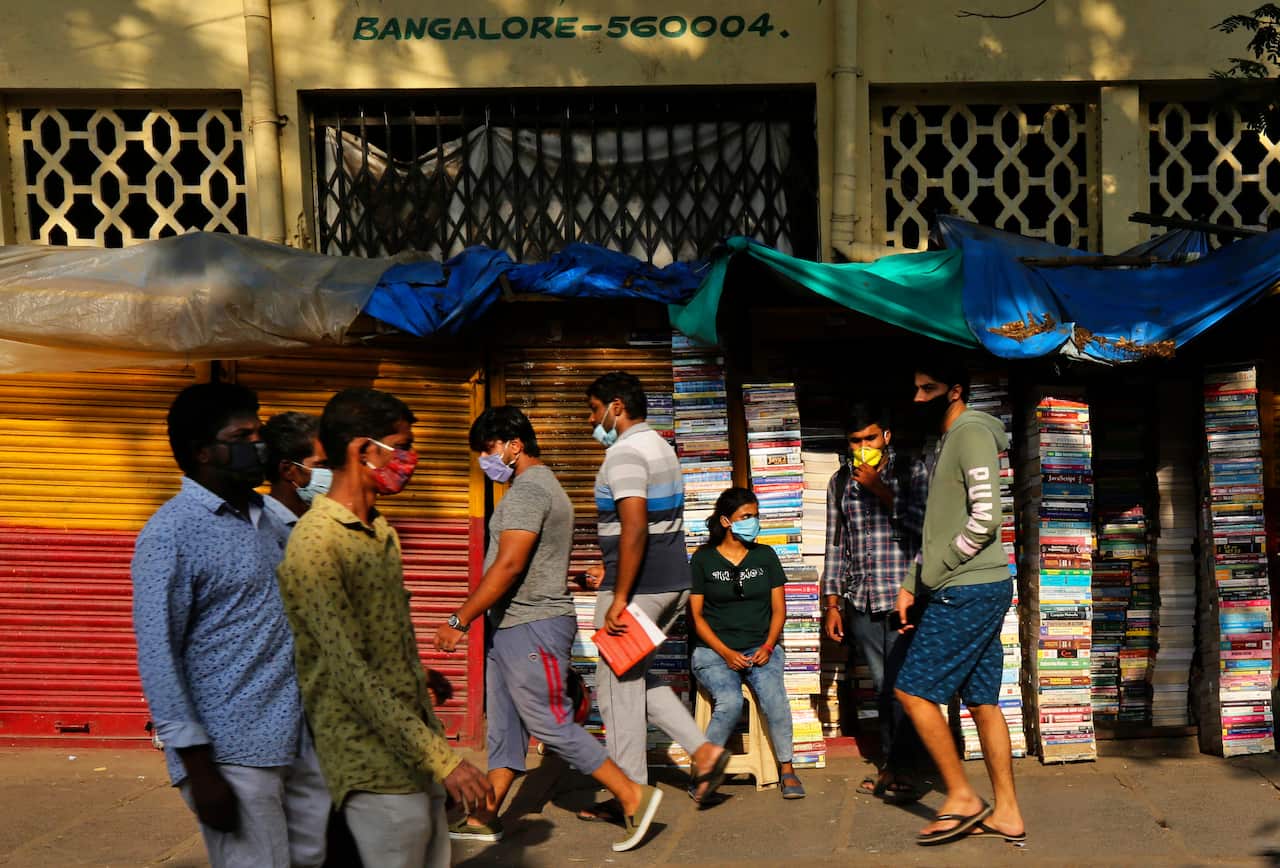 Indians wearing face masks as prevention against coronavirus walk past a roadside bookshop in Bengaluru, India.