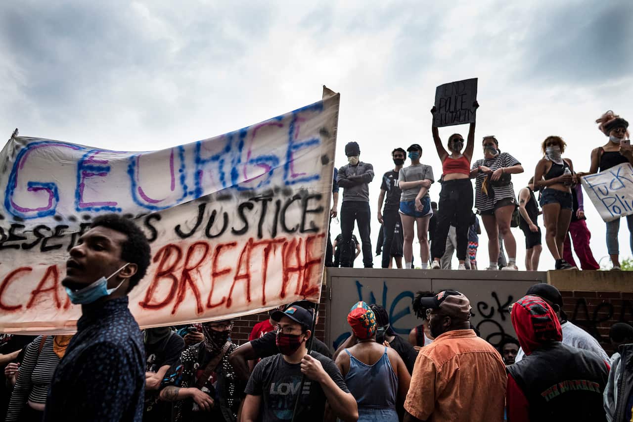 Protesters stand outside the Minneapolis 3rd Police Precinct station.
