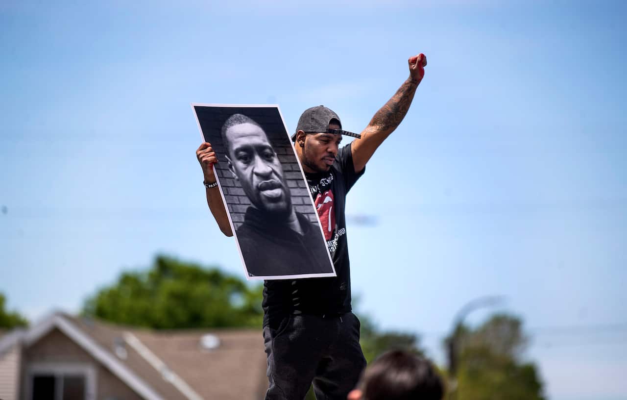 A supporter holds a photo of George Floyd on the site where the 46-year-old died in police custody. 