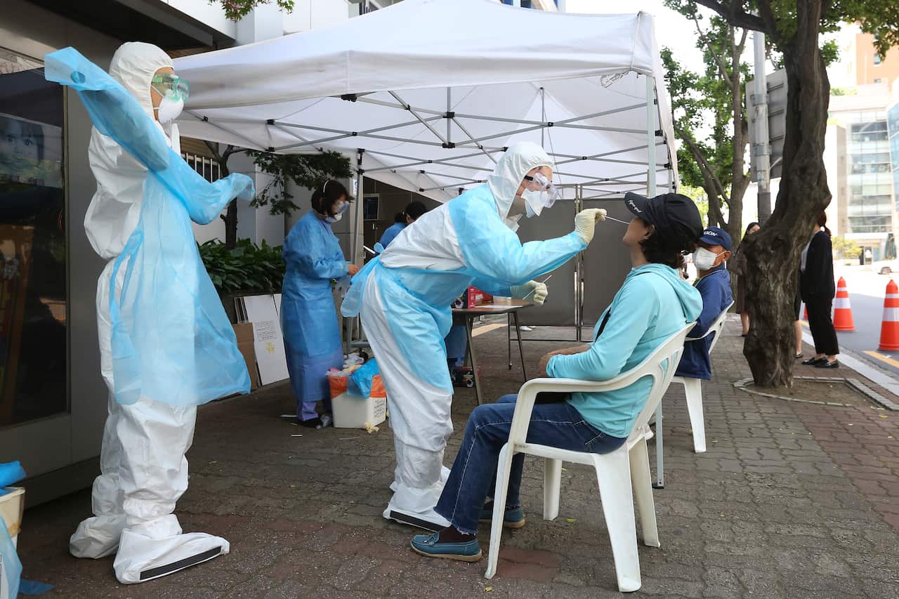 A medical staff wearing protective suits takes samples from a woman during the COVID-19 testing at a hospital in Seoul, South Korea, Friday, May 29, 2020.  South Korea has reported dozens of new cases of the coronavirus, all in the densely populated Seoul